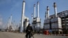 FILE - Iranian oil worker rides his bicycle at the Tehran's oil refinery south of the capital Tehran, Iran. Energy-poor Turkey relies on Iran's oil and is the largest importer of Iranian natural gas. 
