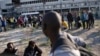 FILE - Migrants line up as they wait to be evacuated from a makeshift street camp, in Paris, France, July 7, 2017.