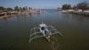 FILE - In this May 7, 2013 photo, a fishing boat returns to their village in the coastal town of Masinloc, Zambales province, northwestern Philippines. 