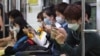 Passengers wear masks as a precaution against Middle East Respiratory Syndrome (MERS) as they use their smartphones on a subway train in Seoul, South Korea, June 8, 2015. 