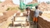 ក្មេងប្រុសពីរនាក់កំពុង​លើ​ដុំ​ឥដ្ឋ​ដាក់​លើ​រទេះ​ឈើមួយ នៅ​សិប្បកម្មឡឥដ្ឋមួយកន្លែងនៅប្រទេស​កម្ពុជា។ (រូបថតដោយ Licadho)