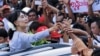 Burma's pro-democracy leader Aung San Suu Kyi touches the hands of her supporters as she arrives to attend the opening ceremony of her National League for Democracy (NLD) party's branch office in Yangon, May 23, 2012. 