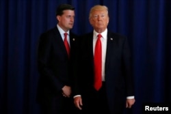 El Secretario de Personal de la Casa Blanca, Rob Porter (izquierda). recuerda al presidente Donald Trump que olvidó firmar una ley después que el mandatario se retirara rápidamente, luego de hacer declaraciones a periodistas en su campo de golf en Bedminster, Nueva Jersey. Aug.12, 2017.