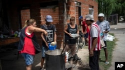 La pobreza agobia a millones de argentinos, y los maestros se oponen a reformas del presidente Milei, en la imagen, voluntarios sirven almuerzos calientes en el comedor social "Regalo de Dios" en el barrio Libertador de Buenos Aires, Argentina, el jueves 22 de febrero de 2024.