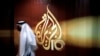 ARCHIVO: Un empleado de la cadena de televisión qatarí Al Jazeera camina frente al logo del canal en Doha, Qatar.