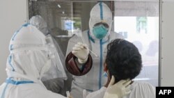 A medical staff take a swab sample of a journalist to test for COVID-19 coronavirus at a quarantine facility in Hlaing University in Yangon in preparation the 73rd anniversary of Martyrs' Day ceremony on July 16, 2020. (Photo by Ye Aung THU / AFP)