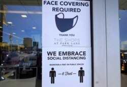 Signs tells customers about safety measures against COVID-19 that are required inside a retail store Tuesday, March 2, 2021, in Dallas.