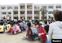 Estudiantes sentados en un patio de recreo después de ser evacuados del edificio escolar tras un terremoto en Ikeda, Osaka, oeste de Japan, el lunes, 18 de junio de 2018.