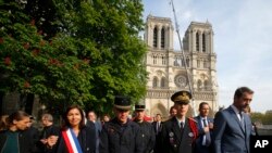 El ministro del Interior francés, Christophe Castaner, a la derecha, la alcaldesa de París, Anne Hidalgo, a la izquierda, y otros funcionarios, caminan por la catedral de Notre Dame.