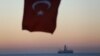 FILE - The Turkish national flag hangs in the foreground as drilling vessel Fatih is seen off the Mediterranean resort city of Antalya, Turkey.