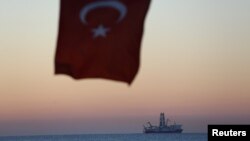 FILE - The Turkish national flag hangs in the foreground as drilling vessel Fatih is seen off the Mediterranean resort city of Antalya, Turkey.