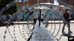 Un periodista, con una máscara protectora, camina por una calle desierta durante un cierre del gobierno que restringe a los residentes a realizar compras esenciales por las mañanas, en un intento por contener la propagación del nuevo coronavirus.