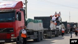 Trabalhadores do Crescente Vermelho Palestino descarregam camiões que transportam ajuda humanitária depois de entrarem na Faixa de Gaza vindos do Egipto através da passagem de fronteira de Rafah, 21 de outubro de 2023.