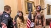 Los partidarios del entonces presidente Donald Trump, incluido Jacob Chansley, con sombrero de piel, son confrontados por agentes de la policía del Capitolio de EEUU, fuera de la Cámara del Senado, en Washington, el 6 de enero de 2021.