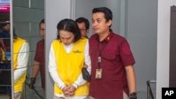 Petugas imigrasi mengawal Yusuke Yamazaki, kiri, buronan asal Jepang yang dicari karena kasus penipuan di negara asalnya, sebelum dideportasi di Batam, Selasa, 12 Maret 2024. (Foto: AP)