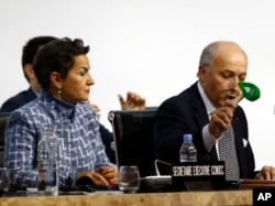 French Foreign Minister and president of the COP21 Laurent Fabius uses to hammer to mark the adoption of the agreement while United Nations climate chief Christiana Figueres looks on.
