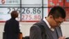 People stand by an electronic stock board of a securities firm in Tokyo, Dec. 3, 2018. Shares are advancing in Asia following the meeting between Presidents Donald Trump and Xi Jinping.