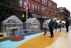 ARCHIVO - En esta foto del 18 de octubre de 2020, la gente camina junto a burbujas de plástico para comer al aire libre en el mercado Fulton en Chicago. Ante un resurgimiento de casos de covid, el gobernador J.B. Pritzker prohibió comer y beber en interiores en Chicago.