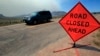 File - Smoke rises in the background as a motorist drives down Larimer County Highway 74W as a wildfire burns, near Livermore, Colorado.