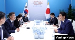 문재인(왼쪽 두번째) 한국 대통령과 아베 신조(오른쪽) 일본 총리가 7일 독일 함부르크 G20 정상회의장에서 양국 정부 관계자들이 배석한 가운데 회담하고 있다.