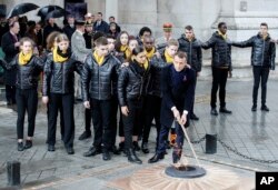 El presidente francés, Emmanuel Macron, acompañado de varios niños enciende la llama en la Tumba del Soldado Desconocido bajo el Arco de Triunfo durante las ceremonias por los 100 años del fin de la Primera Guerra Mundial, el 11 de noviembre de 2018 en París.