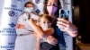 Finn Washburn, 9, poses for a photo with his mother, Kate Elsley, in front of a picture of Dr. Anthony Fauci after he received a COVID-19 vaccine in San Jose, Calif., Nov. 3, 2021. 