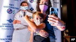 Finn Washburn, 9, poses for a photo with his mother, Kate Elsley, in front of a picture of Dr. Anthony Fauci after he received a COVID-19 vaccine in San Jose, Calif., Nov. 3, 2021. 