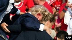 Xüsusi Xidmətin əməkdaşları qulağndan qan axdığı görünən Donald Trampı təşvqiat mitinqində atəş açıqldıqdan sonra səhnədən çıxarır. Batler, Pennsilvaniya. 13 iyul, 2024.