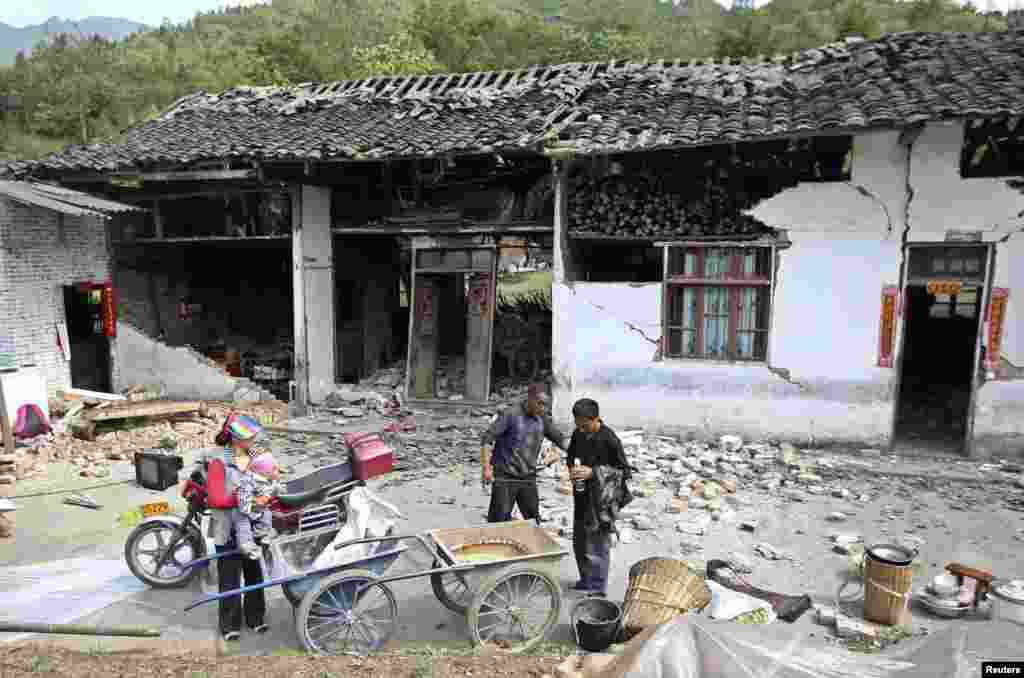 People stand outside a damaged house after a strong 6.6 magnitude earthquake hit, at Longmen village, Lushan county, Ya&#39;an, Sichuan province, Apr. 20, 2013. 