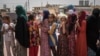 FILE - Women and children stand in line for food at Dibaga camp for internally displaced civilians, in Irbil province, Iraq, Aug. 7, 2016.