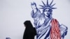 FILE - A woman walks in front of new anti-U.S. murals on the walls of the former U.S. embassy in Tehran, Iran, Nov. 2, 2019. 