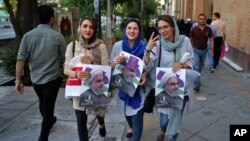 Partidarias del presidente iraní, Hassan Rouhani, portan carteles con su foto en las calles de Teherán, durante la campaña para la votación del viernes, 19 de mayo de 2017.
