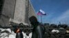 Masked pro-Russian men walk past a barricade outside a regional government building in Donetsk, eastern Ukraine April 21, 2014. An agreement reached last week to avert wider conflict in Ukraine was faltering as the new week began, with pro-Moscow separati