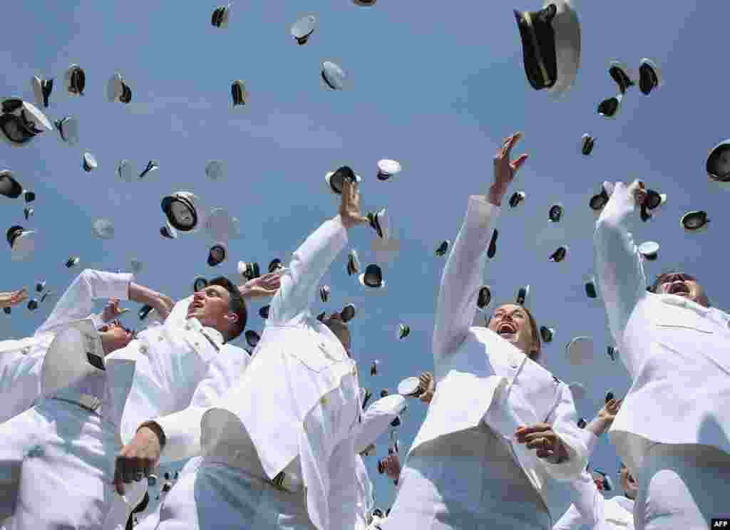 Para wisudawan Akademi Angkatan Laut AS melemparkan topi mereka pada acara wisuda di kota Annapolis, Maryland.