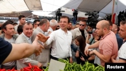 FILE - Ekrem Imamoglu, Istanbul mayoral candidate of the main opposition Republican People's Party (CHP), shakes hands with a vendor at a vegetable market in Istanbul, Turkey, May 29, 2019.