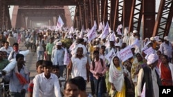 Hindu pilgrims hold religious flags and walk on a crowded bridge after a stampede on the same bridge on the outskirts of Varanasi, India, Oct. 15, 2016.