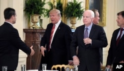 ARCHIVO - El presidente de EE.UU. Donald Trump (segundo a la izquierda), saluda al senador de Indiana Todd Young, mientras el senador John McCain (segundo desde la derecha) observa, en una reunión de senadores republicanos en la Casa Blanca, el 27 de junio de 2017.