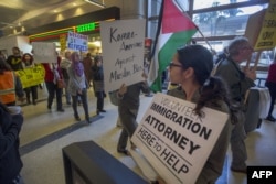 Manifestantes en el aeropuerto de Seattle pasan frente a una abogada voluntaria de inmigración, mientras apoyan el fallo de un juez federal en la ciudad, que suspendió temporalmente una prohibición temporal de viajes ordenada por el presidente Donald Trump contra ciudadanos de siete países de mayoría musulmana y refugiados.