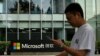 Un hombre usa su teléfono móvil mientras camina frente a la sede local de Microsoft en Beijing el 20 de julio de 2021, un día después de que Estados Unidos acusó a Beijing de llevar a cabo el ataque cibernético contra Microsoft.