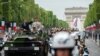 France's President Emmanuel Macron gestures in his command car next to French Armies Chief Staff General Francois Lecointre as they review troops before the start of the Bastille Day military parade down the Champs-Elysees avenue in Paris, July 14, 2019.