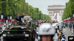 France's President Emmanuel Macron gestures in his command car next to French Armies Chief Staff General Francois Lecointre as they review troops before the start of the Bastille Day military parade down the Champs-Elysees avenue in Paris, July 14, 2019.