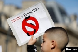 FILE - A young boy holds up a placard during a protest against President Abdelaziz Bouteflika seeking a fifth term in a presidential election set for April 18, in Paris, France, Feb. 24, 2019.