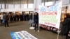 FILE - Protesters display a banner to protest against the financing of the Dakota Access oil pipeline by Swiss banks UBS and Credit Suisse as participants arrive ahead of the annual shareholder meeting of Swiss bank UBS in Basel, Switzerland, May 4, 2017. The banner reads "UBS + Credit Suisse destroy the Standing Rock Native American reserve." 