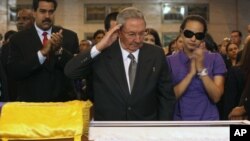 In this photo released by Miraflores Press Office, Cuba's President Raul Castro salutes as he stands next to the coffin of Hugo Chavez at a military academy in Caracas, March 7, 2013. 