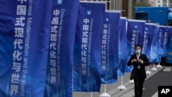一名男子走過上海街頭插滿的宣傳旗幟：“中國式現代化與世界”。 （2023年4月21日）