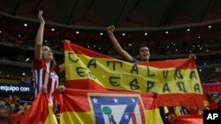 Partidarios del Atlético de Madrid, sostienen una bandera española que dice: "Cataluña es España" durante un partido de fútbol de la Liga española entre el Atlético de Madrid y Barcelona en el estadio Metropolitano de Madrid, España, el 14 de octubre de 2017.