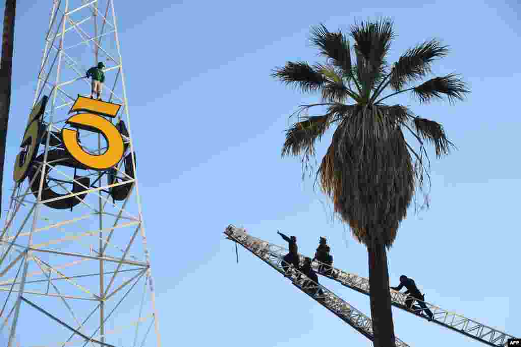 Anggota kepolisian Los Angeles (Kanan) memanjat dua tangga pemadam kebakaran untuk meraih seorang pria yang memanjat menara radio bersejarah KTLA di Hollywood, California, 11 Mei 2016.&nbsp; Selama hampir tiga jam seorang pria mencengkaram kuda-kuda dari menara setinggi 160 kaki (53 meter) yang terletak di Sunset Bronson Studios sebelum diturunkan dengan selamat.&nbsp; Pria tersebut kemudian ditahan polisi untuk keperluan evaluasi kejiwaan.