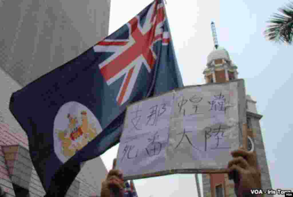 A banner held by a protester reads, 'China locusts, go back to the mainland.' Above, Hong Kong's former British colonial flag is raised by another protester in a gesture of defiance toward the Chinese government. (Iris Tong, VOA)