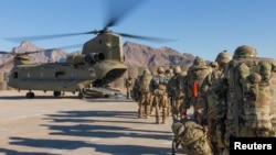 FILE - Soldiers attached to the 101st Resolute Support Sustainment Brigade, Iowa National Guard and 10th Mountain, 2-14 Infantry Battalion load onto a Chinook helicopter to head out on a mission in Afghanistan, Jan. 15, 2019.