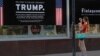 A woman takes a picture of a poster welcoming U.S. President Donald Trump and Russian President Vladimir Putin at a store in downtown Helsinki, July 14, 2018. Trump and Putin will meet Monday at Finnish presidential palace in Helsinki.